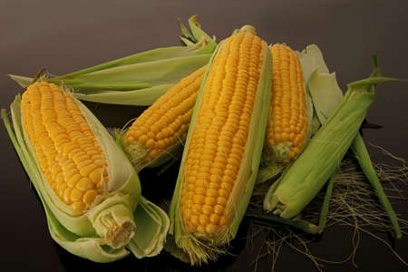 Fresh corns on black glass table.