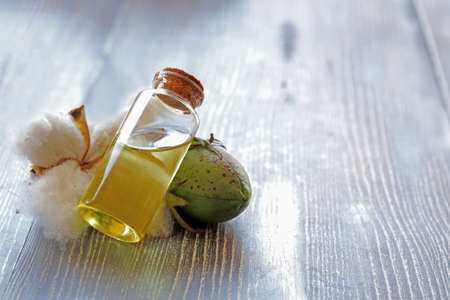 White cottons, cocoons and cottonseed oil in a bottle on a wooden floor.の写真素材