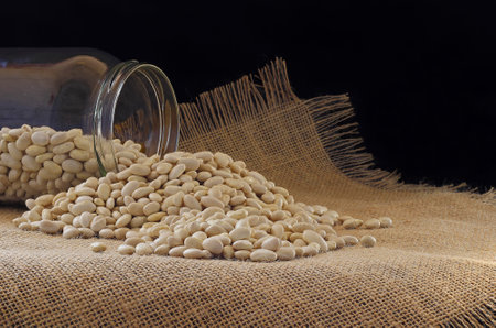 dried beans pouring out of glass jarの写真素材