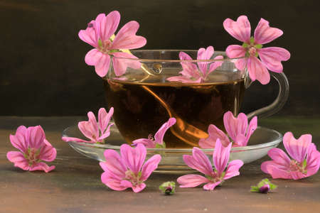 Hibiscus tea and hibiscus flowers in a glass cup on a wooden table. Vitamin tea for colds and flu.