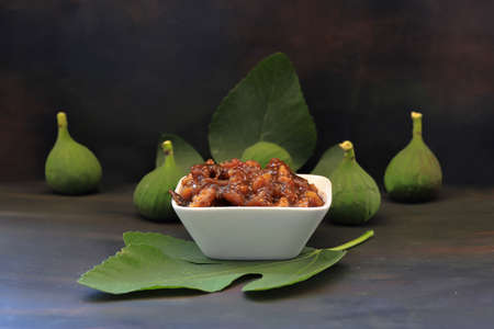 Fig jam and fig fruits on dark wood background