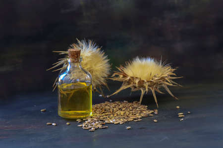 Bottle of tincture or elixir essential oil and thistle flowers on wooden background.