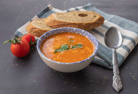 Tomato soup in a bowl on a black background .