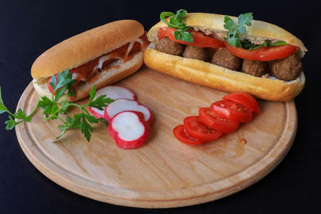 Hot dog - grilled sausage in bun with gravy isolated on black background.Swedish meatballs in breadcrumbsの写真素材