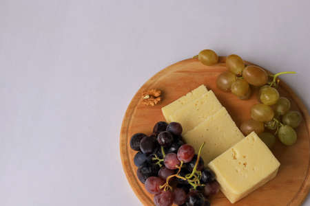 Cheeses on a wooden board . Grapes on a white background .の写真素材