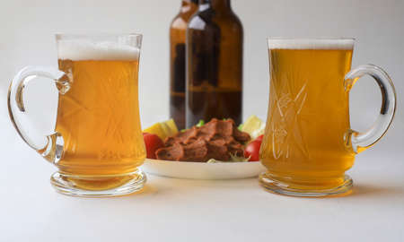 two pint glasses. Out of focus meatball plate in the background.