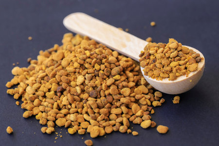 Top view on raw organic bee pollen granules on black background.