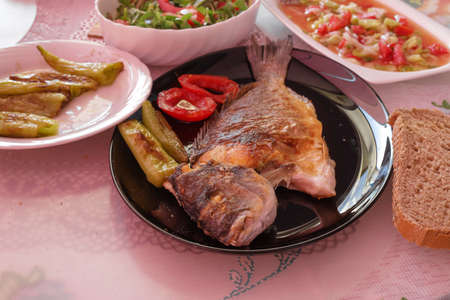 On the table , Fried sea bream in a black plateの写真素材