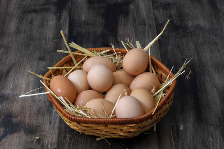 Stack of egg on straw with wooden table background.Top view.