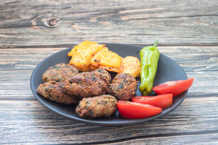 Cyprus meatballs, tomatoes, french fries, peppers. Beautiful presentation on a black plate.の写真素材