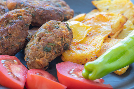 Cyprus meatballs, tomatoes, french fries, peppers. Beautiful presentation on a black plate.の写真素材