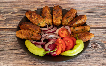 Fried vegetable patties on a plate. Homemade meatballs made of cauliflower garnished with fresh tomatoes, peppers and onions. Vegetarian lunch or dinner idea.の写真素材