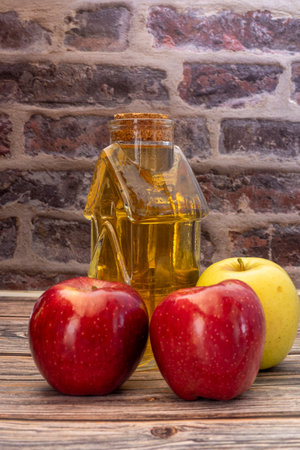 Healthy organic food. Apple cider vinegar in a glass bottle and fresh red and yellow apples on a light background.の写真素材