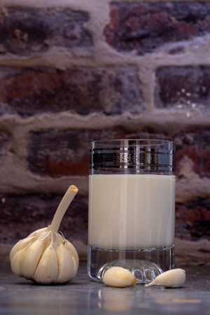 Hot garlic milk in a glass cup with peeled garlic on the backgroundの写真素材