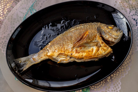 Fried sea bream in a black plate