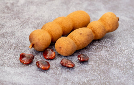 Close-up shot of tamarind fruits and seeds isolated on marble background.の写真素材