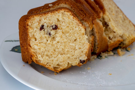 Homemade classic sliced vanilla raisin sponge cake on a white plate .
