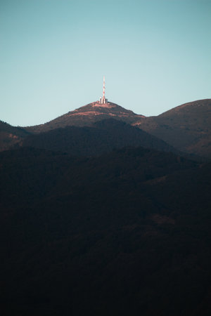 Mountain peak with radio tower on top in the morning light.
