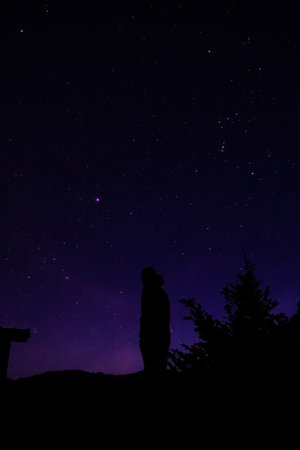 Silhouette of a man looking at the starry night skyの写真素材