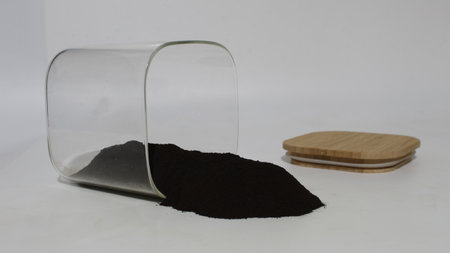 Black walnut hull powder spilled from a jar.の写真素材
