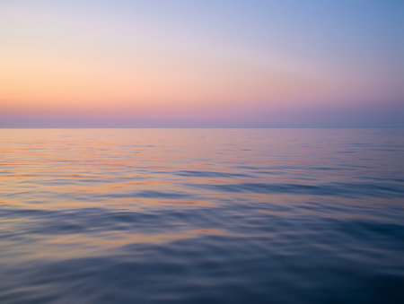 A dreamy coastal scene captures the soft pastels of twilight spreading across the sky and reflecting gently on a serene, smooth shoreline. Shades of pink, lavender, and baby blue streak through the sky and ripple across the wet sands, creating a harmonious blend of color and light. This peaceful moment evokes stillness, clarity, and the quiet beauty of nature.の素材