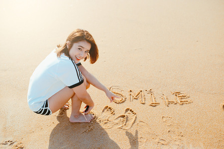 Bueatiful girl write word in the sand on the beach.の写真素材