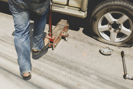 A man changing the wheel at the side of the roadの写真素材