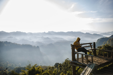 A man sitting on veranda and playing on tablet at view point.の写真素材