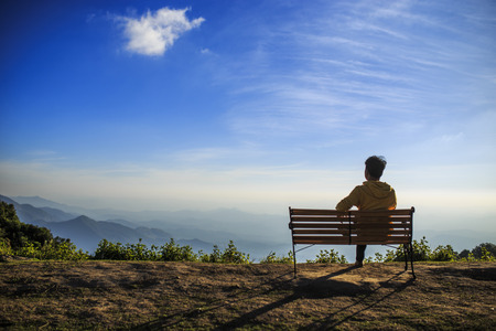 A man sitting on veranda and playing on tablet at view point.