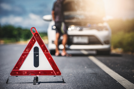 Emergency stop sign and man with broken car on the roadの写真素材