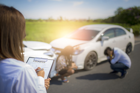 Insurance agent writing on clipboard after accident cars.の写真素材