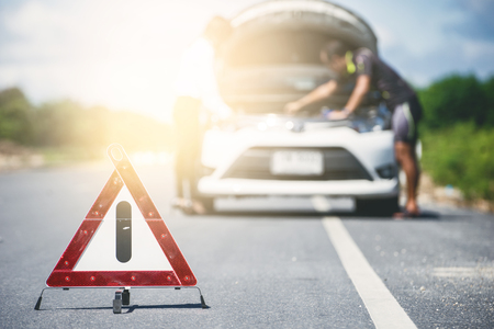 Emergency stop sign and man with broken car on the roadの写真素材