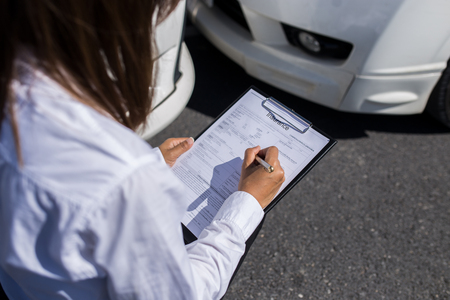 Insurance agent writing on clipboard after accident cars.の写真素材