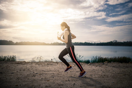 young fitness woman running on the road in the morning.の写真素材