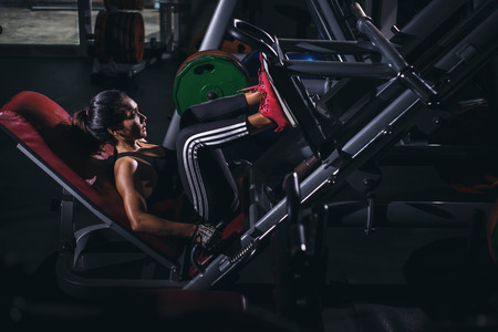 Strong Asia woman execute exercise with exercise-machine in gym.