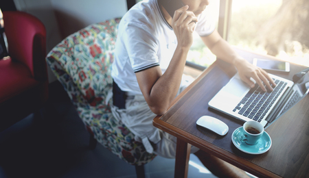 A working man talking on the phone with someone and he used laptop for working in coffee shop.の写真素材