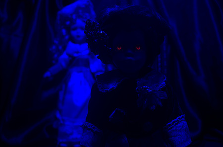 Horror dolls blue light. Creepy horror photo of a two old fashioned dolls standing with curtain background.の写真素材
