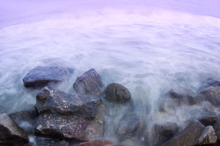 Landscape photo of a long exposed seashore waves hitting rocks.の写真素材
