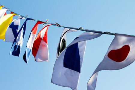 Photo of a various country flags weaving on wind and blue sky on a background.の写真素材