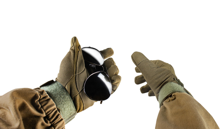 Isolated photo of a first person view arms in tactical jacket and gloves holding black sunglasses on white background.の写真素材