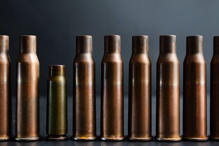 Concept photo of automatic rifle gun shells standing in line with one smaller gun shell.の写真素材