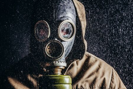 Photo of a stalker face in soviet gas mask in rain on black background.の写真素材