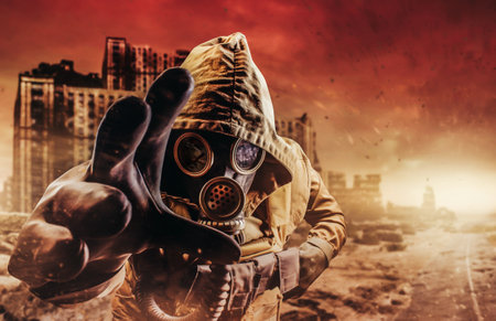 Photo of a stalker in jacket and gloves in damaged gas mask with filter reaching out his hand to camera on destructed apocalyptic wasteland city background.の写真素材