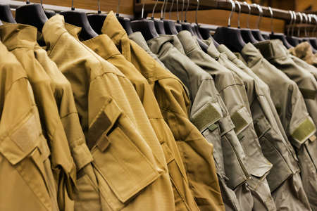 olive colored military shirts and ripstoprs hanging in military store rack.の写真素材