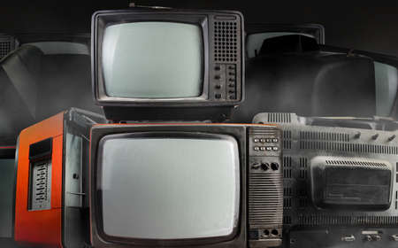 Photo of old fashioned tv sets stacked on dark foggy background.の写真素材