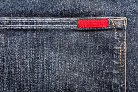 Texture backdrop photo of blue colored denim cloth with red label.の写真素材
