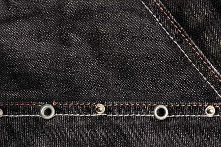 Texture backdrop photo of denim jeans cloth with seams and metal elements.