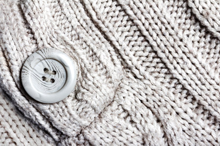 Texture backdrop photo of white colored knitted fabric cloth with button.