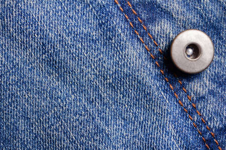 Texture backdrop photo of blue colored denim cloth with seam and metal button.の写真素材