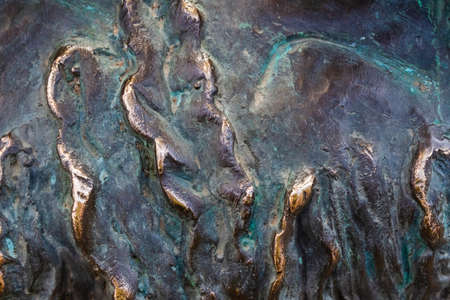 Close-up photo texture of worn and aged copper or bronze statue material with folds.の写真素材